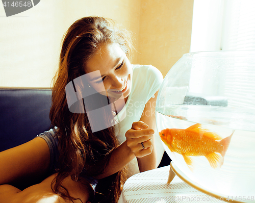 Image of pretty woman smiling playing with goldfish at home, sunlight morning, lifestyle people concept