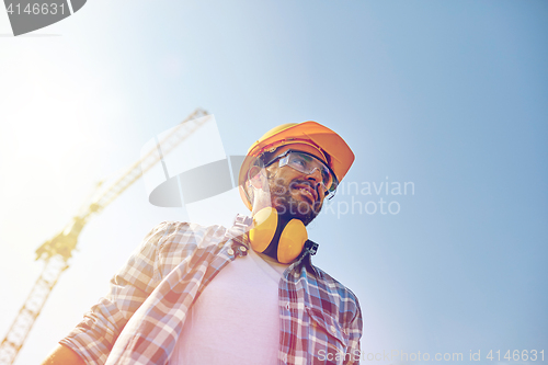 Image of smiling builder with hardhat and headphones