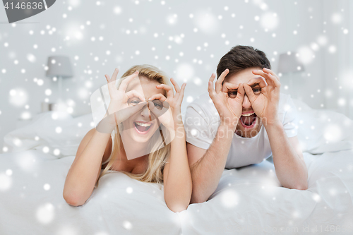 Image of happy couple lying in bed at home