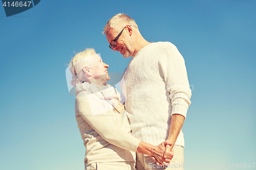 Image of happy senior couple holding hands outdoors