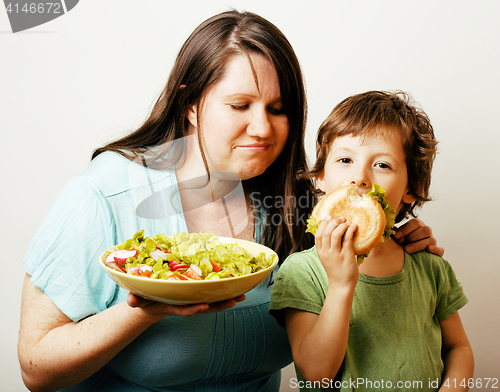 Image of mature woman holding salad and little cute boy with hamburger te