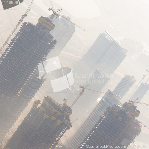 Image of Skyscrappers construction site with cranes on top of buildings.