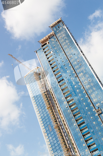 Image of Skyscrappers construction site with cranes on top of buildings.