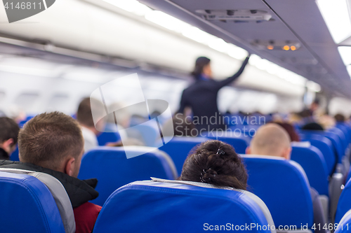 Image of Stewardess walking the aisle of commercial airplane.