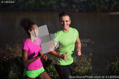 Image of young smiling multiethnic couple jogging in the city