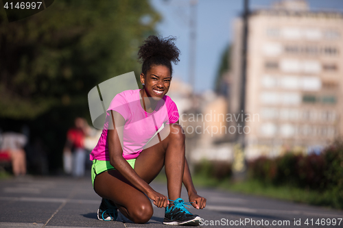 Image of African american woman runner tightening shoe lace