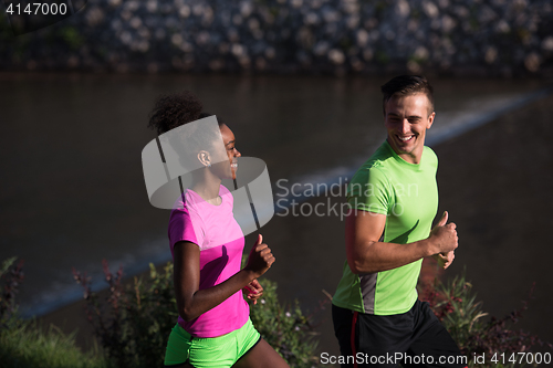 Image of young smiling multiethnic couple jogging in the city