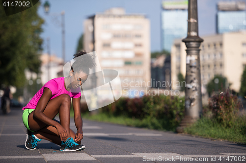 Image of African american woman runner tightening shoe lace