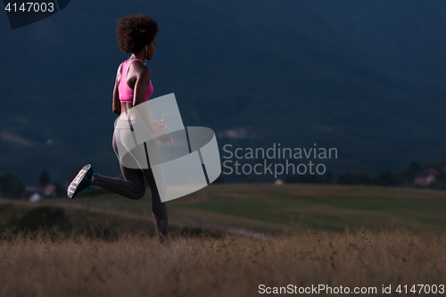 Image of Young African american woman jogging in nature