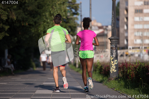 Image of young smiling multiethnic couple jogging in the city
