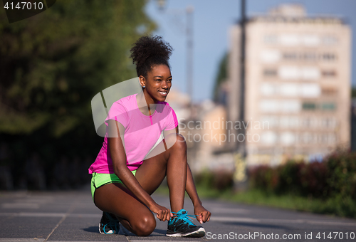 Image of African american woman runner tightening shoe lace