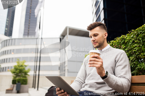 Image of man with tablet pc and coffee on city street bench