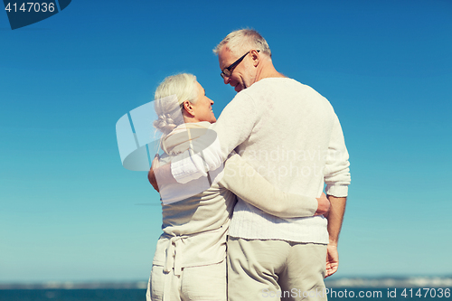 Image of happy senior couple hugging on summer beach