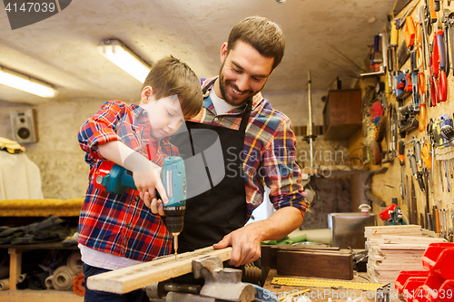 Image of father and son with drill working at workshop