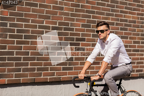 Image of young man riding bicycle on city street