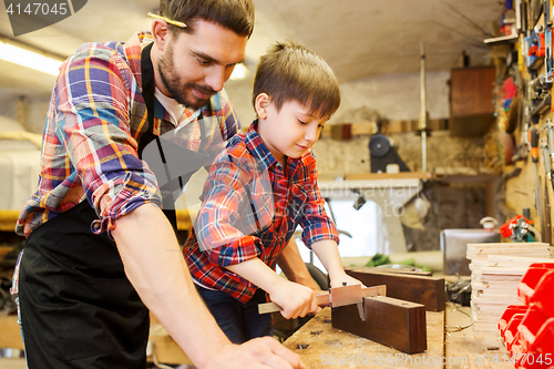 Image of boy and dad with calipers measure wood at workshop