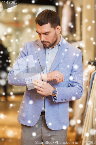 Image of young man trying jacket on in clothing store