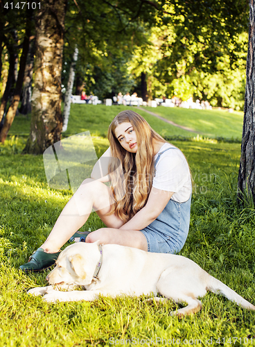 Image of young attractive blond woman playing with her dog in green park 