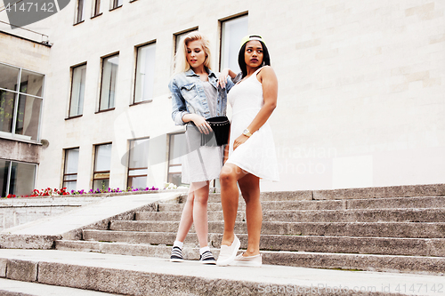 Image of Two teenage girls infront of university building smiling, having