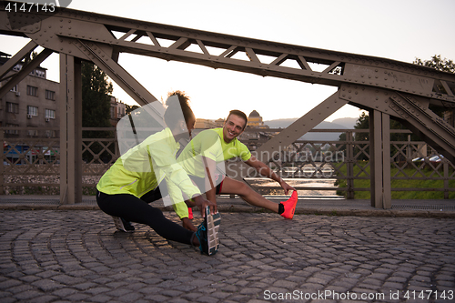 Image of jogging couple warming up and stretching in the city