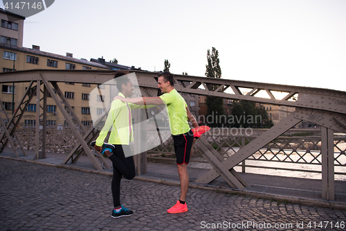 Image of jogging couple warming up and stretching in the city