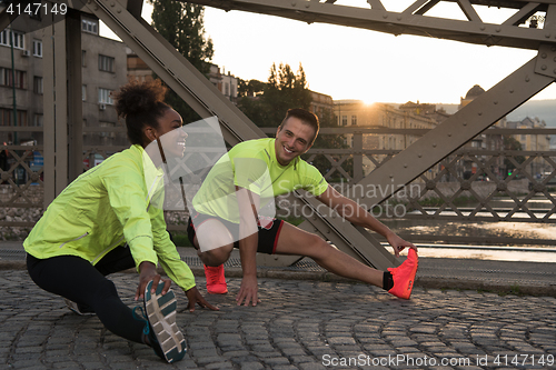 Image of jogging couple warming up and stretching in the city