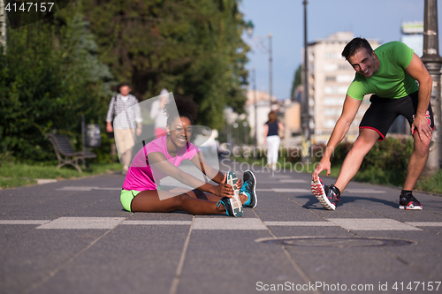 Image of jogging couple warming up and stretching in the city