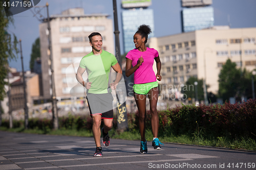 Image of young smiling multiethnic couple jogging in the city