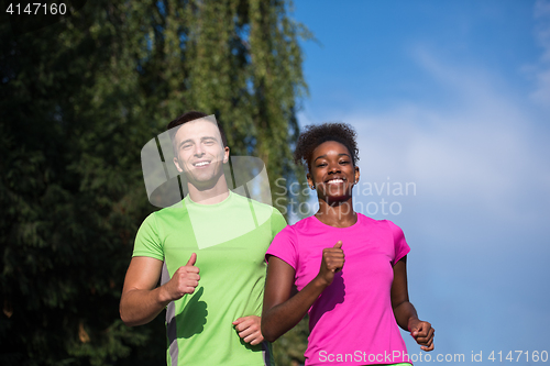 Image of young smiling multiethnic couple jogging in the city