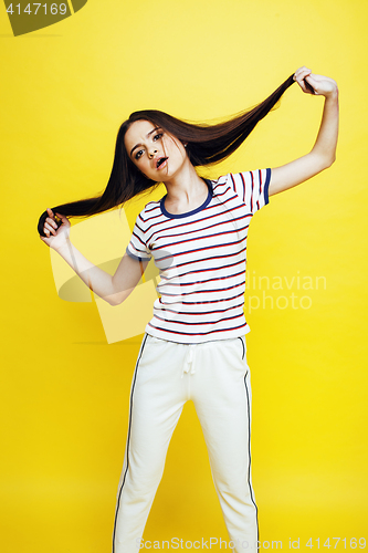 Image of young pretty teenage woman emotional posing on yellow background, fashion lifestyle people concept