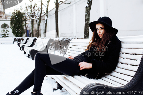 Image of young pretty modern hipster girl waiting on bench at winter snow park alone, lifestyle people concept