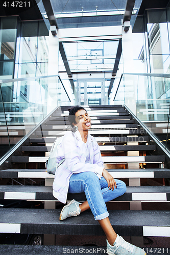 Image of young cute modern indian girl at university building sitting on stairs reading a book, wearing hipster glasses, lifestyle people concept