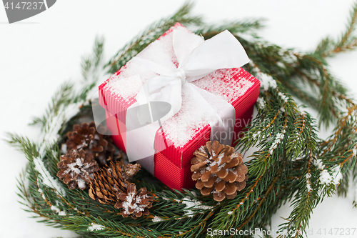 Image of christmas gift and fir wreath with cones on snow