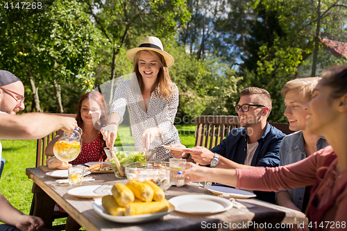 Image of happy friends having dinner at summer garden party