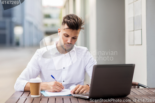 Image of man with laptop and coffee at city cafe