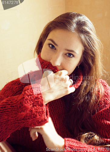 Image of young pretty real woman in red sweater and scarf all over her fa