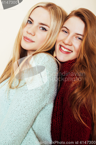 Image of Two young girlfriends in winter sweaters indoors having fun. Lif