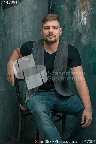 Image of Portrait of smiling happy man sitting on the chair in studio