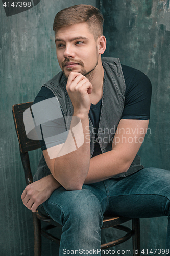 Image of Portrait of serious man sitting on the chair in studio