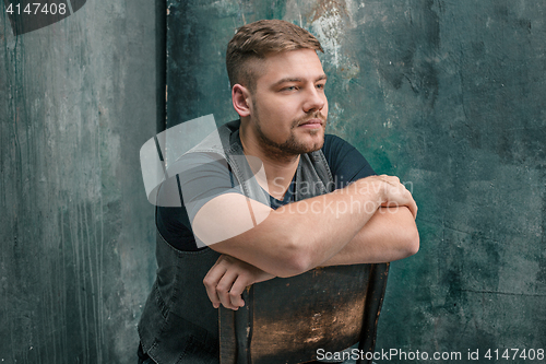 Image of Portrait of serious man sitting on the chair in studio