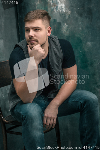 Image of Portrait of smiling happy man sitting on the chair in studio