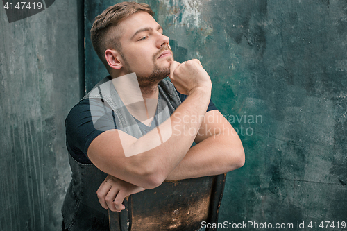 Image of Portrait of serious man sitting on the chair in studio