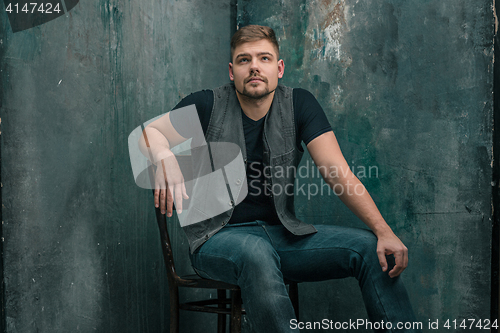 Image of Portrait of serious man sitting on the chair in studio