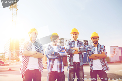 Image of group of smiling builders in hardhats outdoors