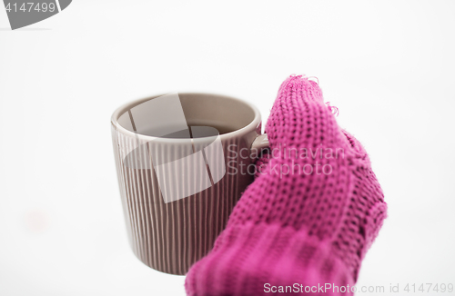 Image of close up of hand in winter mitten holding tea mug