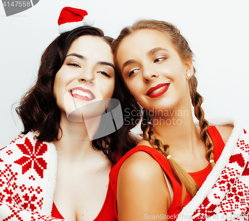 Image of young pretty happy smiling blond and brunette woman girlfriends on christmas in santas red hat and holiday decorated plaid, lifestyle people concept