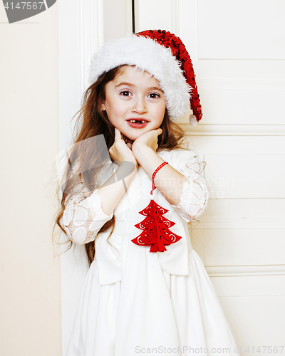 Image of little cute girl in santas red hat waiting for Christmas gifts. 