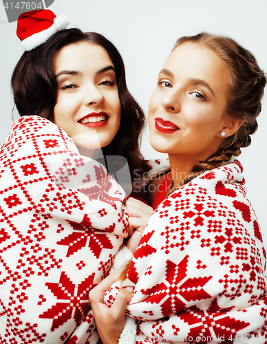 Image of young pretty happy smiling blond and brunette woman girlfriends on christmas in santas red hat and holiday decorated plaid, lifestyle people concept