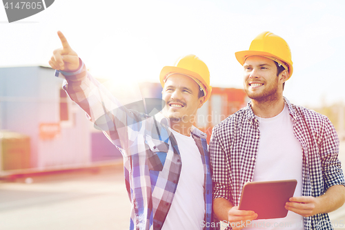 Image of smiling builders in hardhats with tablet pc