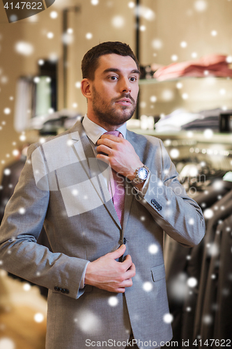 Image of young man trying suit on in clothing store